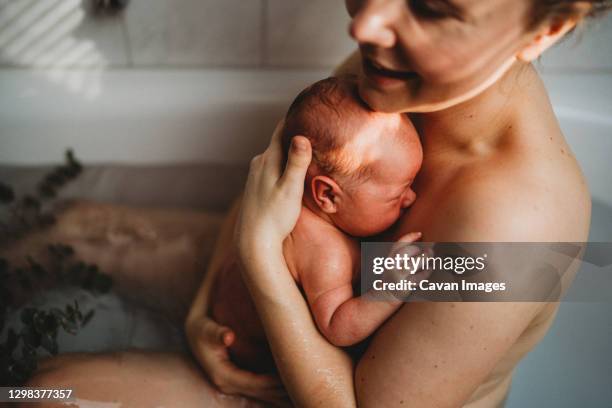 happy smiling mother holding her newborn baby after being born at home - home birth stock-fotos und bilder