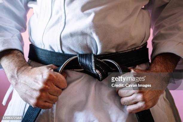 unrecognizable karateka with black belt in firm position - judo stockfoto's en -beelden
