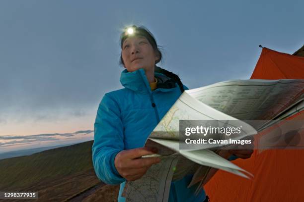 female hiker reading hiking map on pen y fan in wales at sunrise - one person in focus stock pictures, royalty-free photos & images