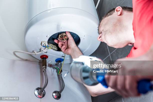 man in bathroom repairing electric boiler - caldeira imagens e fotografias de stock