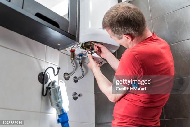 man in bathroom repairing electric boiler - home water heater stock pictures, royalty-free photos & images