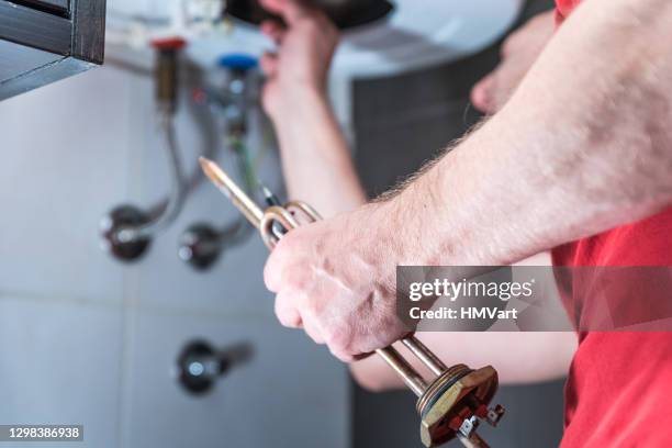 homme dans la salle de bains réparant la chaudière électrique - boiler repair photos et images de collection