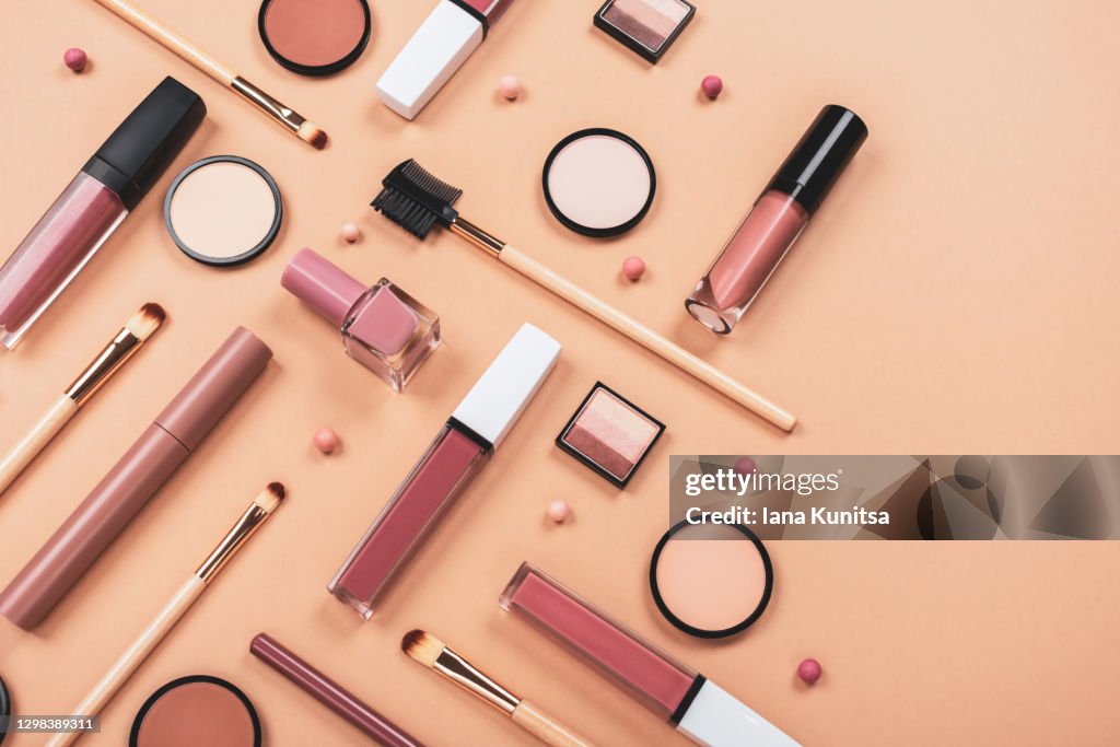 Set of different makeup accessories on beige, brown background. Knolling concept. Cosmetic products for skin care. Eyeshadow, blush, face powder, nail polish, brushes and lipstick.