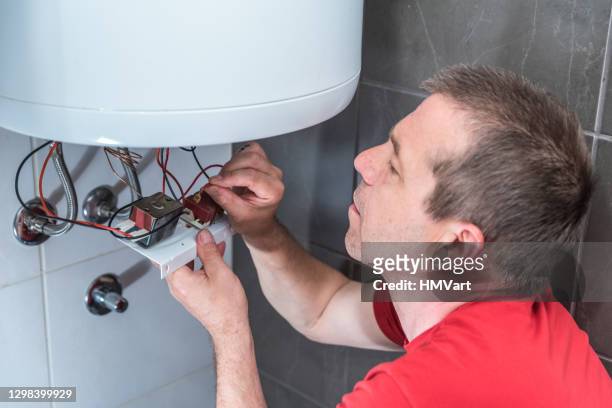 man in bathroom repairing electric boiler - home water heater stock pictures, royalty-free photos & images