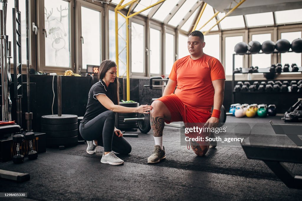 Female personal trainer showing her male trainee right way to exercise