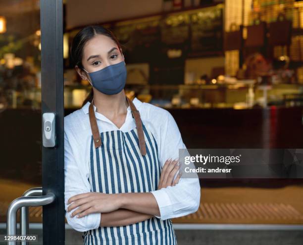 waitress wearing a facemask at a restaurant and waiting for clients during the pandemic - australia covid stock pictures, royalty-free photos & images