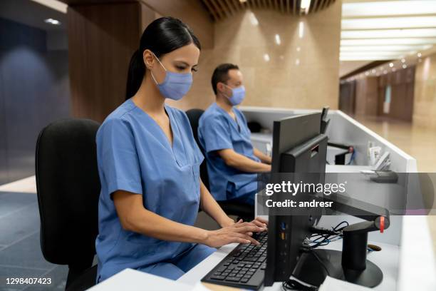 happy receptionist working at a hospital wearing a facemask - nurse station stock pictures, royalty-free photos & images