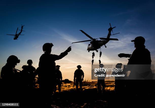 silhouettes of soldiers on military mission at dusk - forças armadas especiais imagens e fotografias de stock