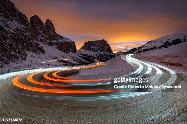 sunset on snowy sassolungo and car trails lights, south tyrol - hairpin curve stock-fotos und bilder