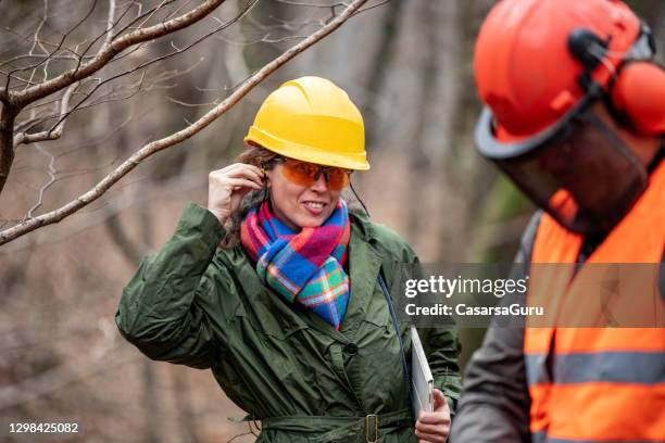 female forester foreman inserting ear protectors - inserting stock pictures, royalty-free photos & images
