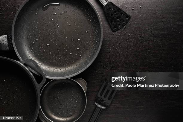 black frying pans with a non-stick teflon coating on black background - pentola foto e immagini stock