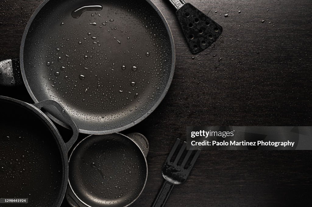 Black frying pans with a non-stick teflon coating on black background