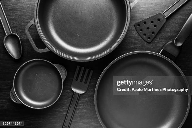 black frying pans with a non-stick teflon coating on black background - panela utensílio imagens e fotografias de stock