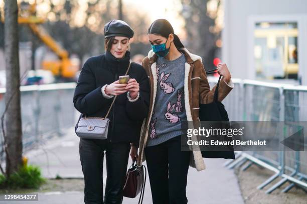 Model wears a black leather beret hat, a black puffer winter jacket, a gray quilted leather Chanel bag ; a model wears a blue and green protective...