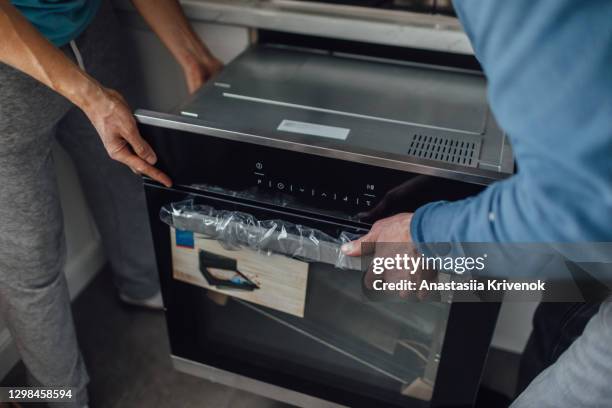 close up photo of two men fixing oven in kitchen. - home appliances stock pictures, royalty-free photos & images