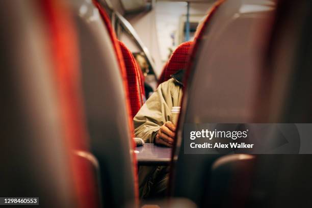 view between seats on train of person holding coffee cup - treincoupé stockfoto's en -beelden