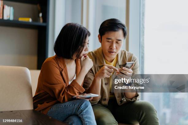 asian chinese couple looking at smartphone and having a discussion - couple talking stock pictures, royalty-free photos & images