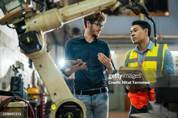 software engineer explaining to controlling robotic welding process to welder in factory. - robotic welding stock pictures, royalty-free photos & images