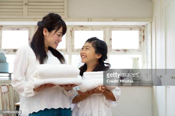 parent and child standing with laundry - mother daughter towel fotografías e imágenes de stock
