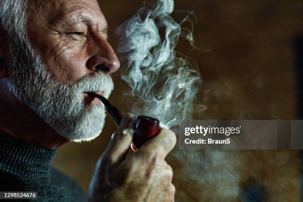 grave uomo maturo che fuma una pipa. - pipa prodotto a base di tabacco foto e immagini stock