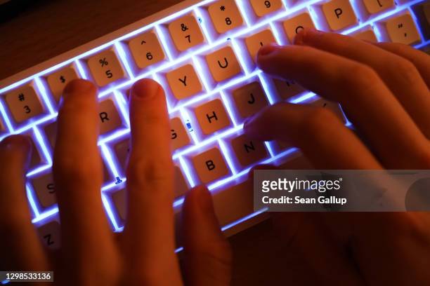 In this photo illustration a young man types on an illuminated computer keyboard typically favored by computer coders on January 25, 2021 in Berlin,...