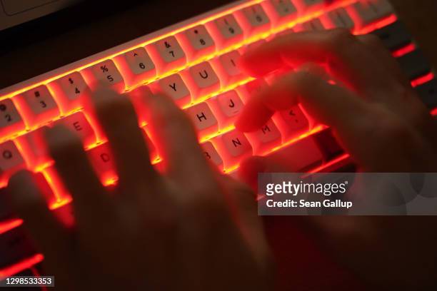 In this photo illustration a young man types on an illuminated computer keyboard typically favored by computer coders on January 25, 2021 in Berlin,...