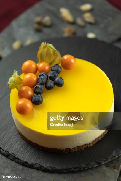 decorated mango cheesecake with cape gooseberry and blueberries - cheesecake stock pictures, royalty-free photos & images