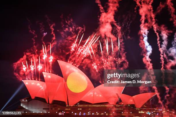 The Australian Aboriginal flag is projected onto the sails of the Sydney Opera House as fireworks explode during an Australia Day show on January 26,...