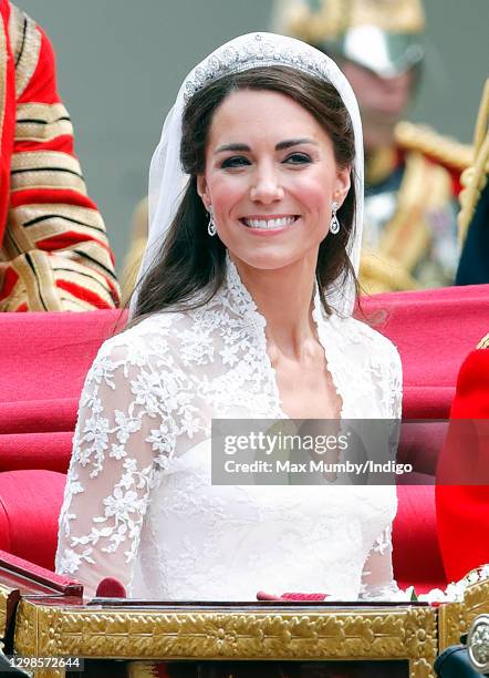 Catherine, Duchess of Cambridge travels down The Mall, on route to Buckingham Palace, in the 1902 State Landau horse drawn carriage following her and...