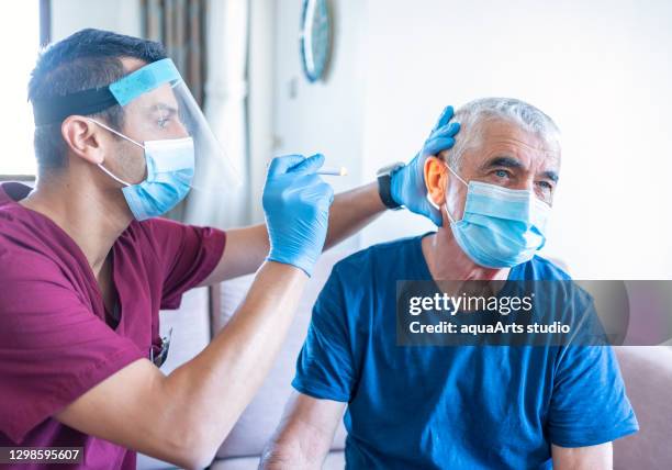 health worker examine ear of senior man in his house during coronavirus epidemic. home care - vertigo stock pictures, royalty-free photos & images