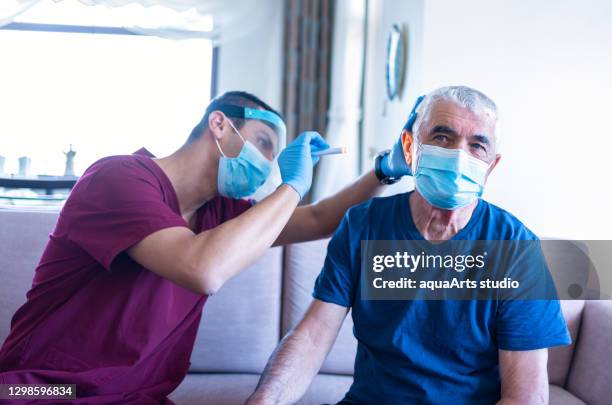 male health worker examine ear of senior man in his house during coronavirus epidemic. home care - vertigo stock pictures, royalty-free photos & images