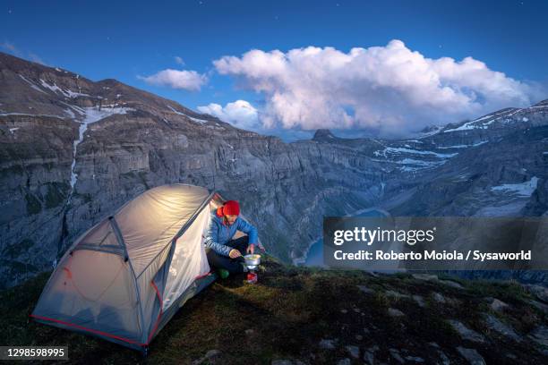 hiker cooking out of tent above lake limmernsee, switzerland - stausee stock-fotos und bilder