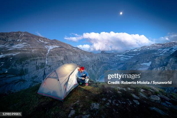 hiker with tent cooking above lake limmernsee, switzerland - camping stove stockfoto's en -beelden