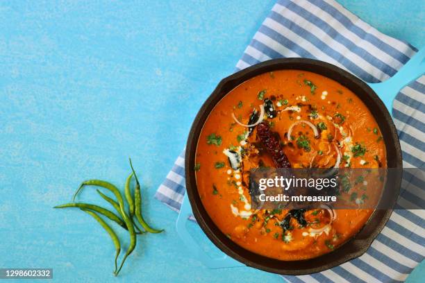 image of indian butter chicken / tikka curry served in turquoise blue cooking pan filled with large chunks of chicken breast meat in curry sauce with garnish of red onion slices and mustard seeds, lachha paratha (layered flatbread) - cooking indian food stock pictures, royalty-free photos & images