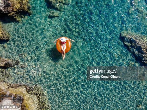 beautiful woman relaxing on inflatable mattress in sea. - blue lagoon imagens e fotografias de stock