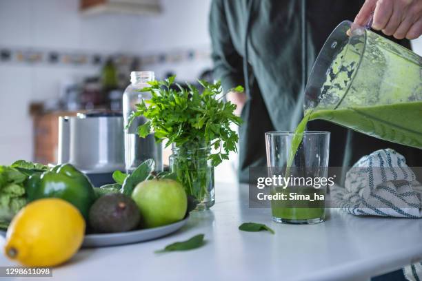 frau bereitet grünen smoothie in der küche - avocado smoothie stock-fotos und bilder