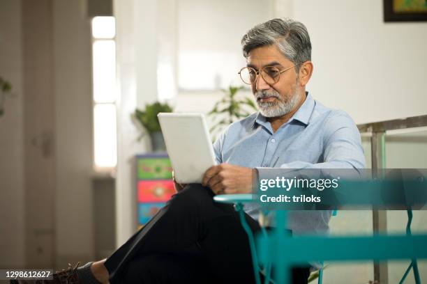 messagerie texte d’homme d’affaires utilisant la tablette numérique - daily life in india photos et images de collection