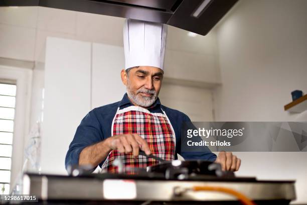 male chef cooking at kitchen - indian chef stock pictures, royalty-free photos & images