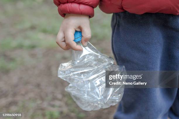 little boy holding a plastic bottle in the forest - reciclar stock pictures, royalty-free photos & images