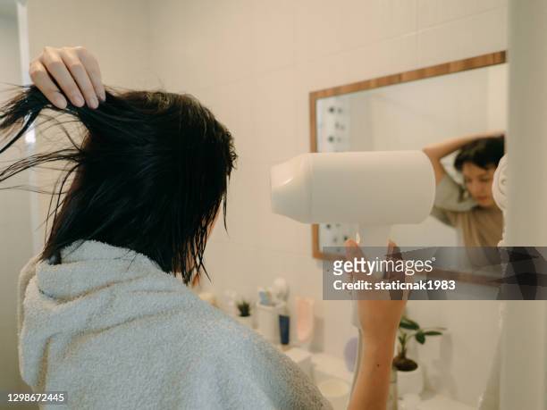femelle asiatique séchant ses cheveux avec un sèche-cheveux. - cheveux secs photos et images de collection