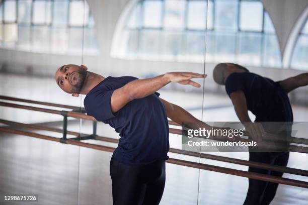 männliche balletttänzerin streckt sich zurück in barre im tanzstudio - balletttänzer männlich stock-fotos und bilder