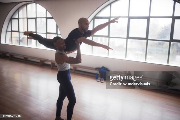 männliche tänzerin hält partner auf posieren auf der luft im studio - turner contemporary stock-fotos und bilder