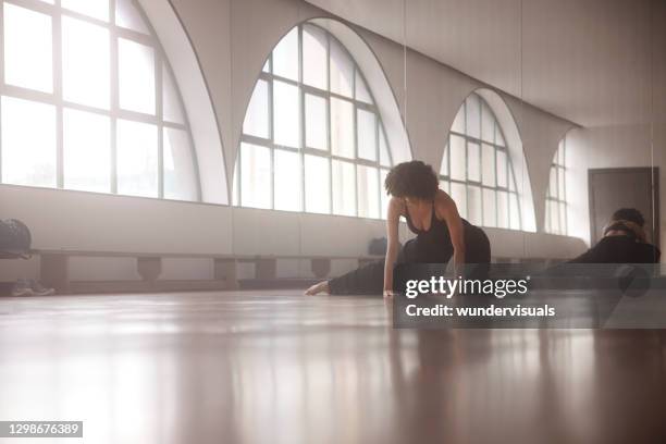 mujer afroamericana estirando la pierna en el suelo en el estudio de baile - dance studio fotografías e imágenes de stock