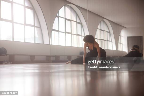 african-american woman stretching leg on floor in dance studio - rehearsal stock pictures, royalty-free photos & images