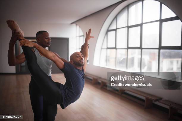 männliche tänzerin unterstützt partner in ballett-routine zusammen im studio - balletttänzer männlich stock-fotos und bilder