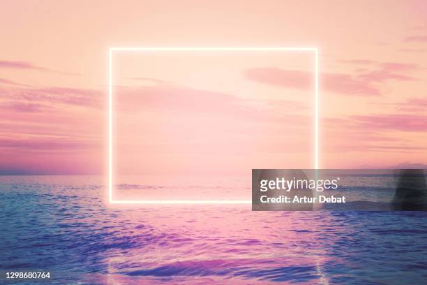 neon square installation glowing over the sea at sunset. - symmetry imagens e fotografias de stock