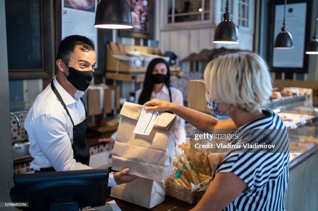 Restaurant-Arbeitgeber verschenken verpackte Lebensmittel an einen Kunden. Wiedereröffnung nach COVID-19 Quarantänekonzepten.
