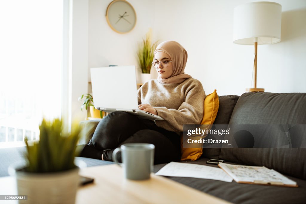 Middle Eastern woman attending online business meeting while working at home