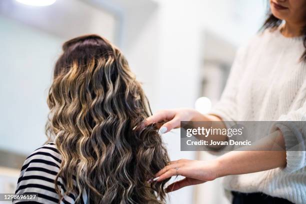 donne con bellissimi capelli lunghi neri al trattamento nel salone parrucchiere - combing foto e immagini stock