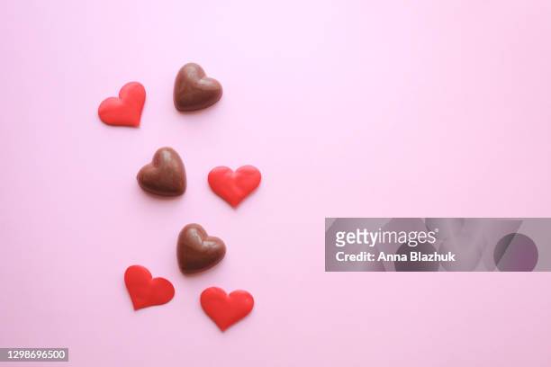 chocolate candies in shape of heart over pink background with copy space for valentine's day greeting card. - chocolate heart stock-fotos und bilder